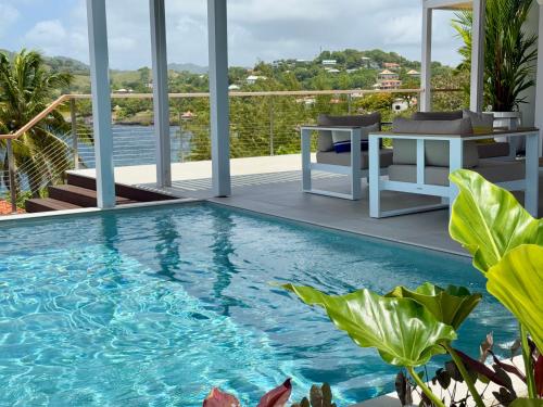 una piscina en un balcón con vistas al agua en EAST KEYS - East Blue Villas, en Le Vauclin