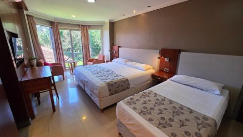 a hotel room with two beds and a desk at HOTEL TROPICAL IGUAZU in Puerto Iguazú