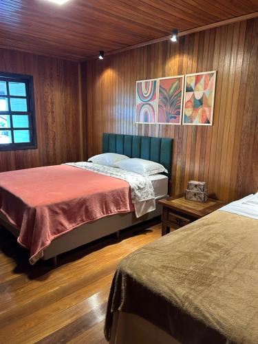two beds in a room with wooden walls at Éden jardim in Guarapuava