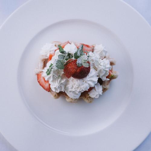 a white plate with a dessert with strawberries and whipped cream at Swiss Diamond Boutique Hotel - La Romantica in Melide