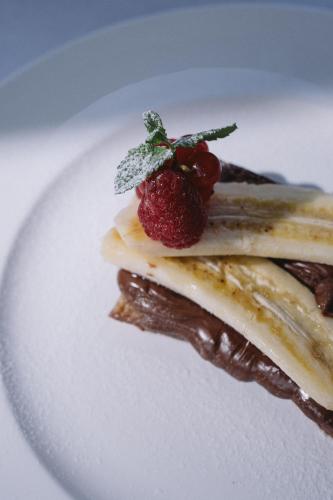 a white plate with a dessert with two strawberries on it at Swiss Diamond Boutique Hotel - La Romantica in Melide