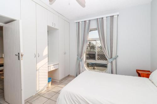 a bedroom with a white bed and a window at Seagull 203 in Margate