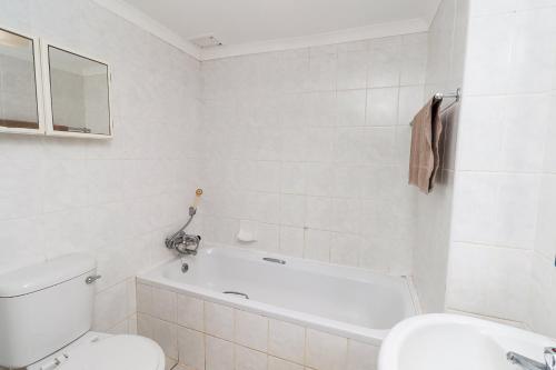 a white bathroom with a toilet and a bath tub at Seagull 203 in Margate