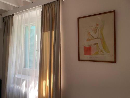 a painting of a woman sitting on a chair next to a window at Peculiar Garden Apartment in Mytilini