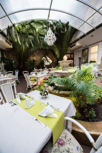 a restaurant with white tables and chairs and plants at Golden Royal Boutique Hotel & Spa in Košice