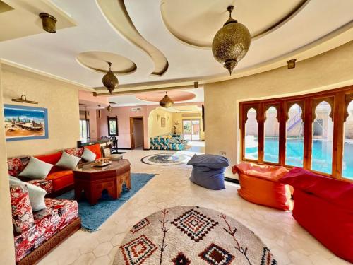 a large living room with red furniture and a ceiling at Dar NFis Suites et chambres de luxe dans un havre de paix vue paradisiaque au bord du lac in Lalla Takerkoust