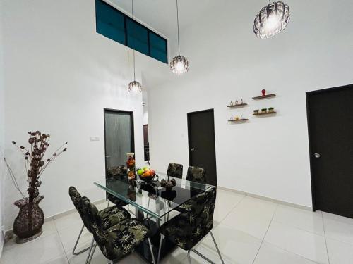 a dining room with a glass table and black chairs at Ethereal Ipoh Homestay in Ipoh