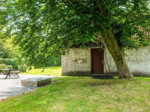 a building with a tree with a swing under it at 6 person holiday home in Løkken in Løkken