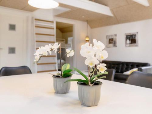 two vases with white flowers sitting on a table at 6 person holiday home in Løkken in Løkken