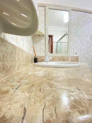 baño con suelo de mármol y lavabo en Pousada Arraial Suites, en Arraial d'Ajuda
