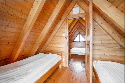 a bedroom with two beds in a wooden attic at Domki Port Jastarnia in Jastarnia