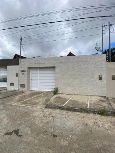 ein großes weißes Backsteingebäude mit zwei Garagentoren in der Unterkunft Temporada CG - Casa altíssimo padrão no Cruzeiro in Campina Grande