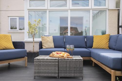 a blue couch and a table with a glass of wine at 4 Bedroom Home with Hot Tub near Gloucester City in Gloucester