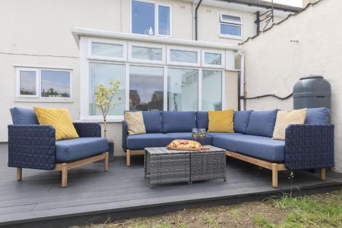 a blue couch and two chairs on a patio at 4 Bedroom Home with Hot Tub near Gloucester City in Gloucester