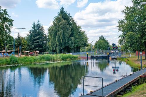 a river with a bridge in a park with trees at Ferienhaus am Rande der Lewitz in Garwitz