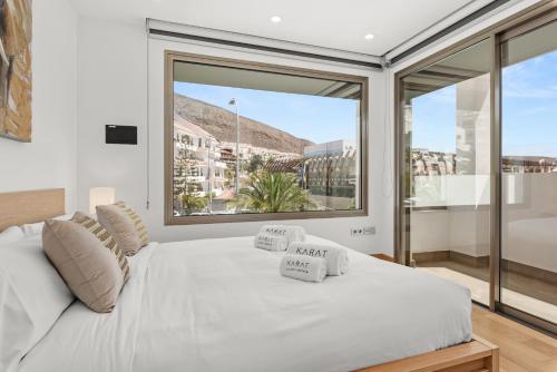 una camera da letto con un letto bianco con una grande finestra di Karat Villa Portofino a Los Cristianos