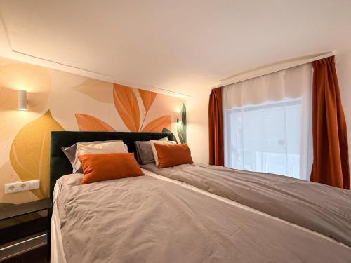 a bedroom with a bed with orange pillows and a window at T25 Urban Green Hideaway in Budapest