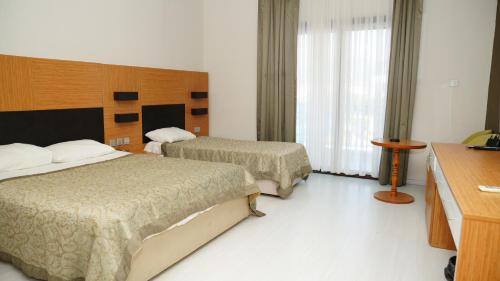 a hotel room with two beds and a desk at Hotel Sempati in Kérynia