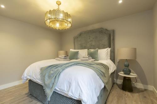 a bedroom with a large bed with a chandelier at Luxury One Bed Annnex on Rodborough Common in Woodchester