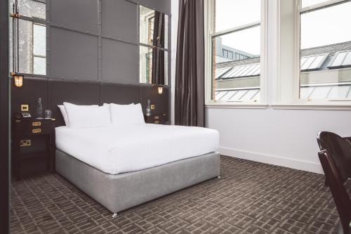 a bedroom with a white bed and two windows at Titanic Hotel Belfast in Belfast