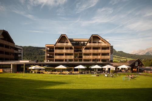 a large building with tables and umbrellas in a field at ADEA Lifestyle Suites Fieberbrunn in Fieberbrunn