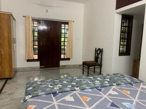 a bedroom with a bed and a chair and windows at SatyaYam Park Villa in Cochin