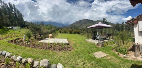 a garden with a bench and an umbrella at La Casita de mi Abuela in Mancos