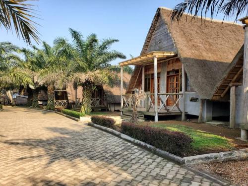 a house with a straw roof and a cobblestone street at Bugoma Palms Resort Sand Beach 