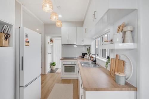 a kitchen with white cabinets and a wooden counter top at Bluewood Cottage - Cozy Charm, Steps from the City in Toowoomba