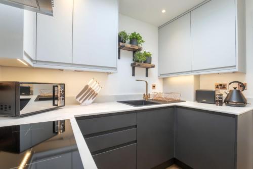 チェルトナムにあるLuxurious 1 Bed Detached Home with Gated Parkingの白いキャビネットと電子レンジを備えたキッチン
