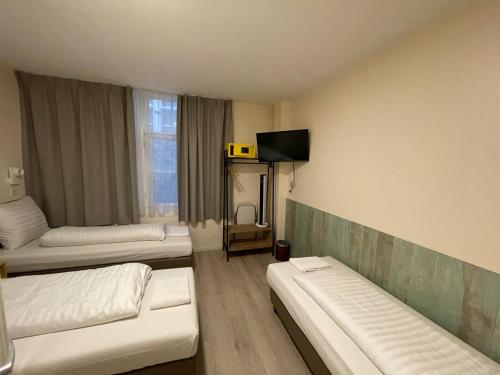 a room with two beds and a tv in it at Hotel Damrak Inn in Amsterdam