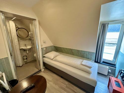 a small bathroom with a shower and a sink at Hotel Damrak Inn in Amsterdam
