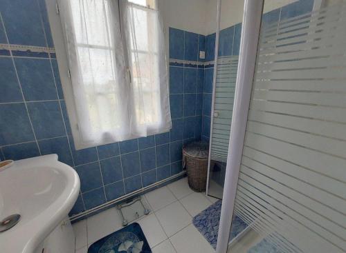 ein blau gefliestes Badezimmer mit Waschbecken und Toilette in der Unterkunft Maison des Hortensias à 500 m des bords de rivière in Limeuil
