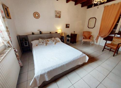ein Schlafzimmer mit einem weißen Bett und einem Stuhl in der Unterkunft Maison des Hortensias à 500 m des bords de rivière in Limeuil