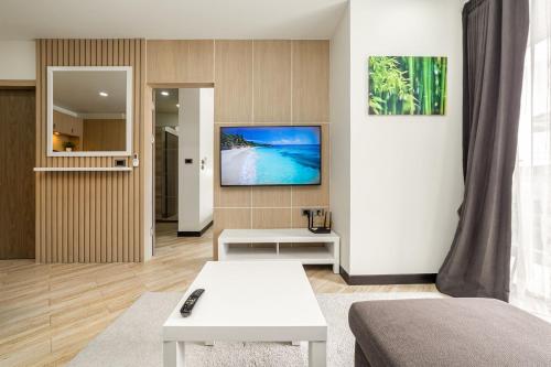 a living room with a tv on a wall at Calypso Garden Residences by Beringela in Phuket Town