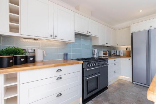 a kitchen with white cabinets and a black stove at Lythwood House in Gloucester