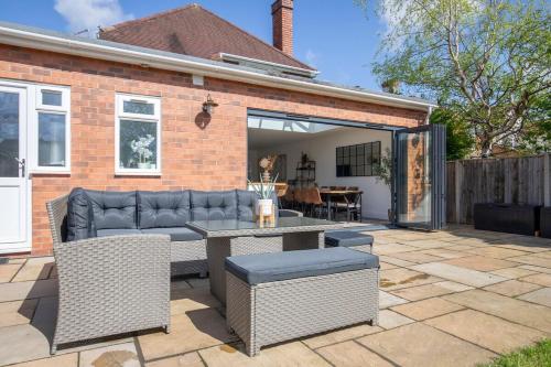 a patio with a couch and a table on a patio at Lythwood House in Gloucester