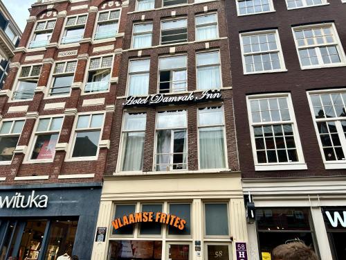 a tall brick building with windows on a city street at Hotel Damrak Inn in Amsterdam