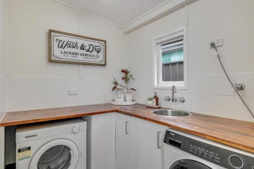 a kitchen with a washing machine and a sink at Bluewood Cottage - Cozy Charm, Steps from the City in Toowoomba
