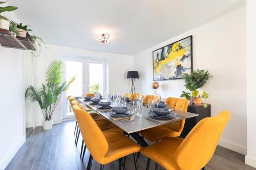 a dining room with a long table and yellow chairs at Modern 4 Bed 3 Bath Home Close to the Town Centre in Gloucestershire