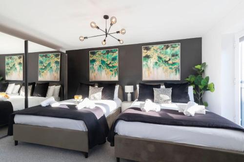 a bedroom with two beds and paintings on the wall at Stunning 4 Bed 3 Bathroom Home in Gloucestershire