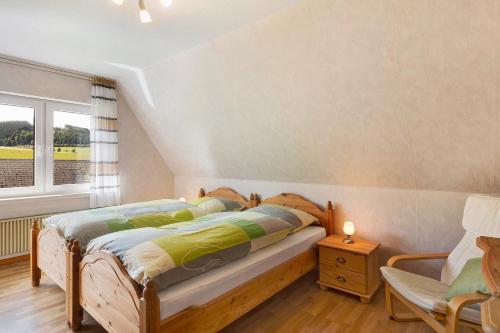 Un dormitorio con una cama y una silla y una ventana. en Ferienwohnung Wallensiepen, en Schmallenberg