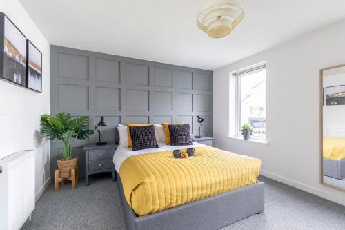 a bedroom with a bed with a yellow blanket at Modern 4 Bedroom 4 Bathroom Home in Cheltenham in Cheltenham