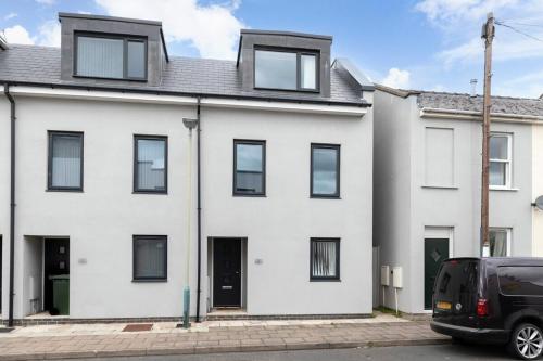 a white house with a car parked in front of it at Modern 4 Bedroom 4 Bathroom Home in Cheltenham in Cheltenham