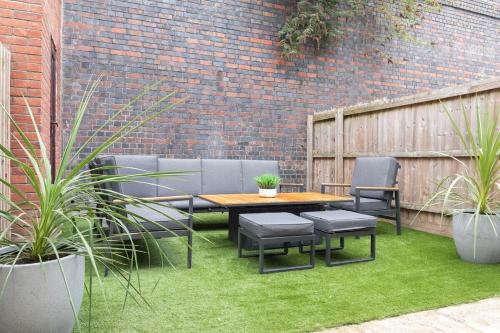 a patio with a table and chairs and a brick wall at Modern 4 Bedroom 4 Bathroom Home in Cheltenham in Cheltenham