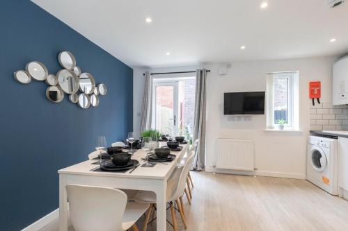 a dining room with a white table and a blue wall at Modern 4 Bedroom 4 Bathroom Home in Cheltenham in Cheltenham
