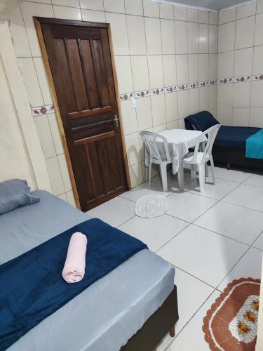 a room with two beds and a table and a door at Kitnet in Araucária