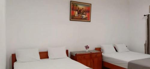 a room with three beds and a picture on the wall at Griya Kulon Yogya in Jetis