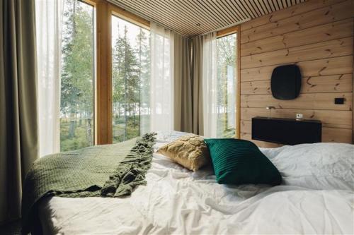 a bed in a bedroom with a large window at Ruka Hideaway by Hilla Villas in Kuusamo