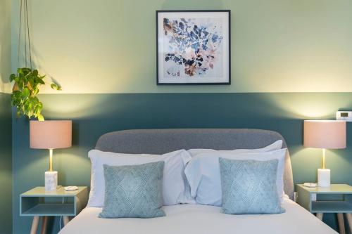 a bedroom with a bed with blue walls and two lamps at Peaceful & Spacious 2 Bed Home in Cheltenham in Gloucestershire